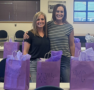 Two ladies in classroom with purple bags with names on them